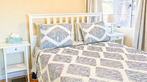 A bedroom with a bed, nightstands, a bedside table, a lamp, a window with curtains, and a wall painting. - Poolside studio in the Foothills with Pool + Hot tub
 (Tucson)