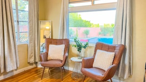 A room with two leather armchairs, a small table with a vase, and a view of a swimming pool. - Poolside studio in the Foothills with Pool + Hot tub
 (Tucson)