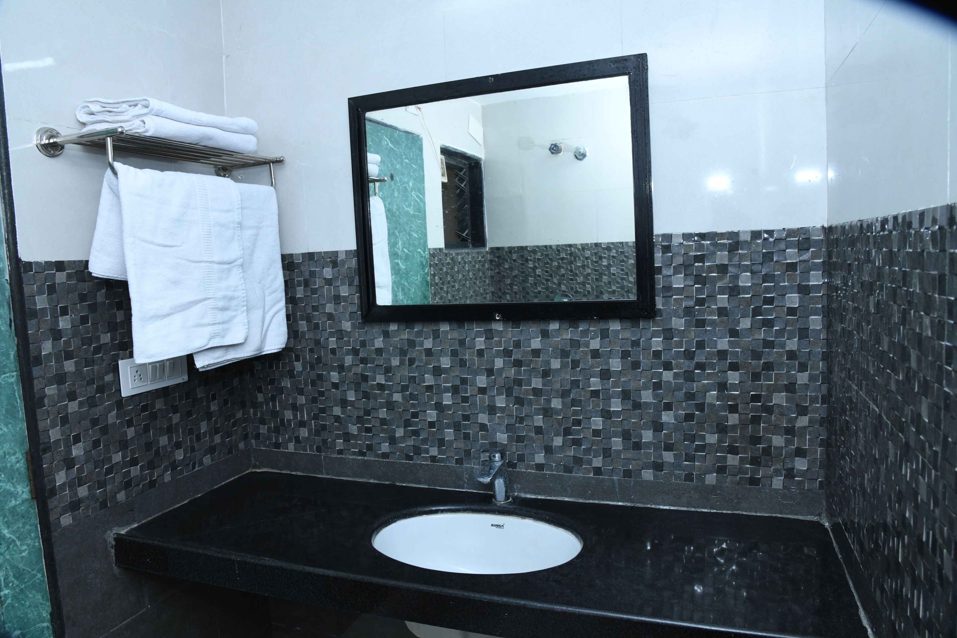 A bathroom with a black sink, a white mirror, and a towel rack with folded towels.
