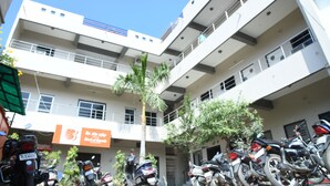A multi-story building with a sign for Bank of Baroda, multiple motorcycles parked in front, and a palm tree. - Hotel durga (Abu Road)