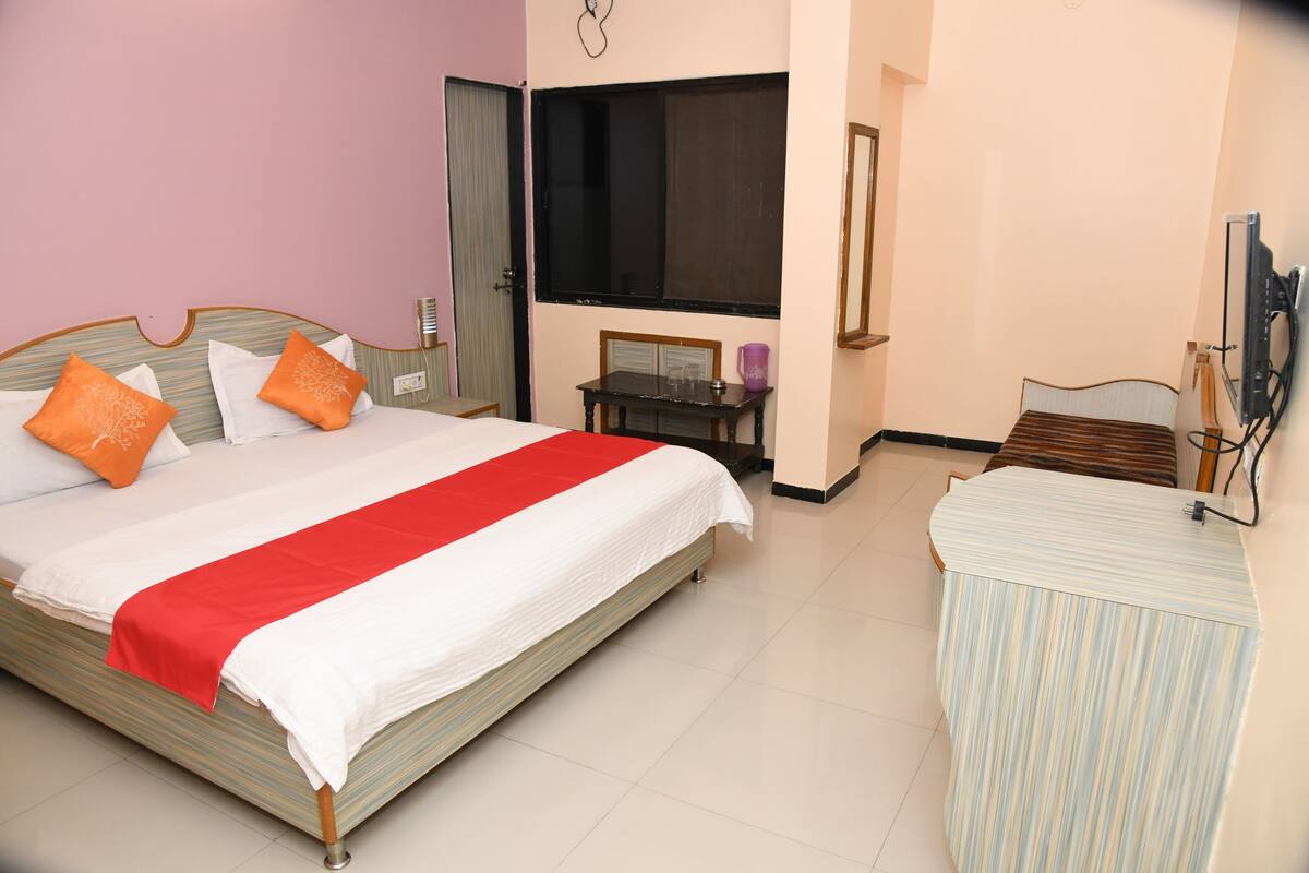 A hotel room with a bed, a desk, and a television.