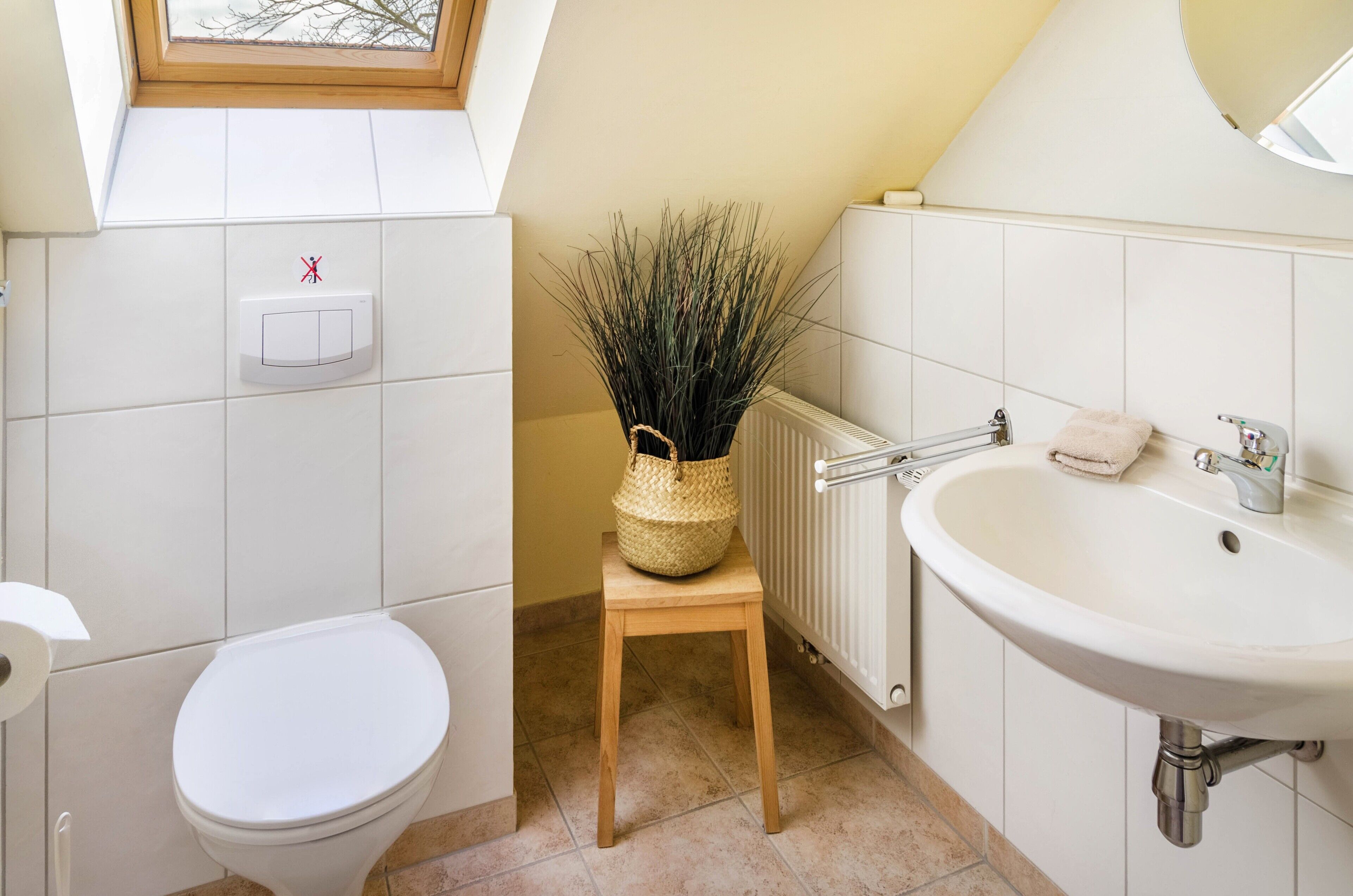 Ein Badezimmer mit Toilette, Waschbecken, Heizkörper und Fenster mit Blick.