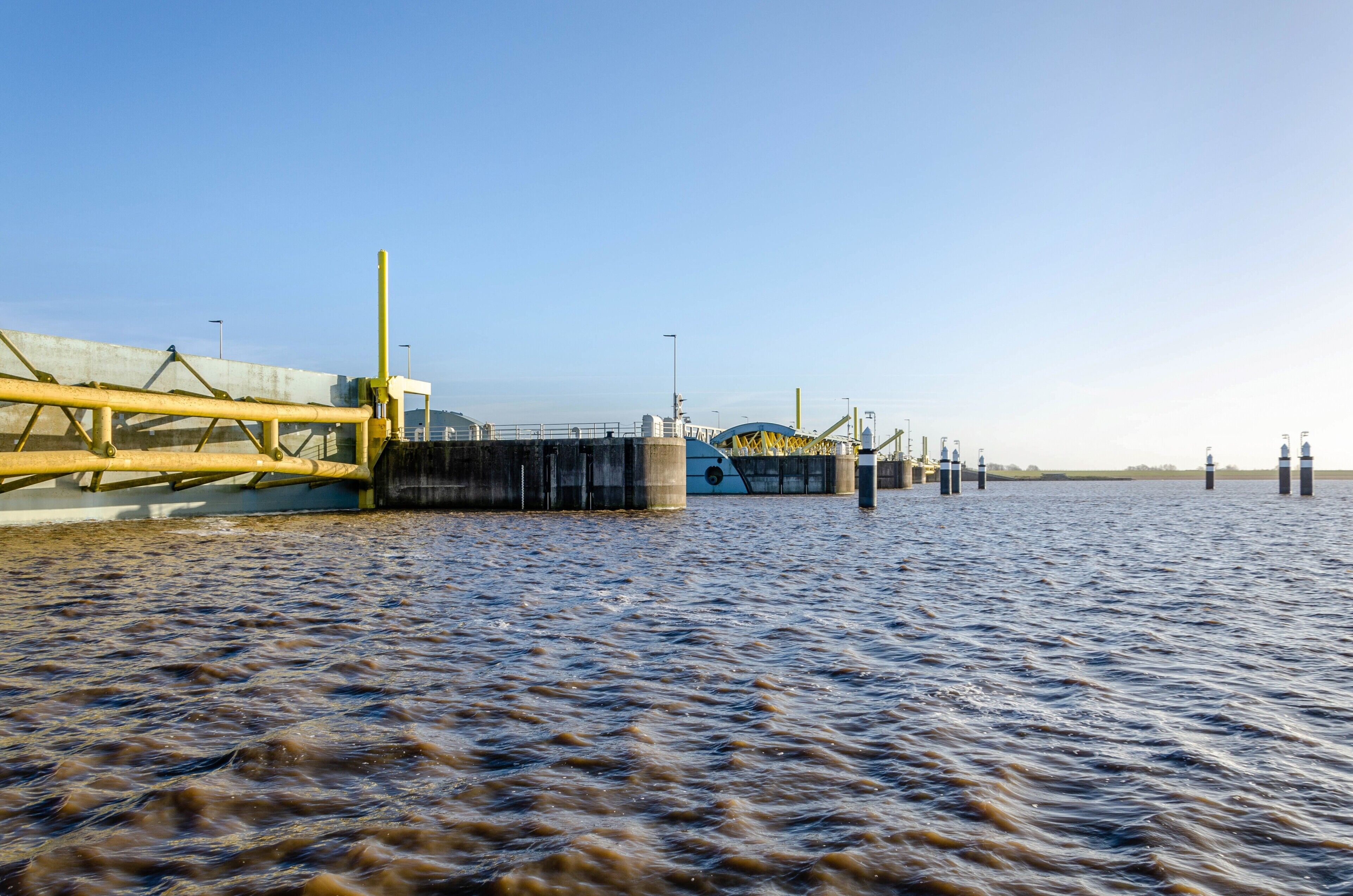 A waterfront structure with a concrete barrier, a water channel, and a clear sky.