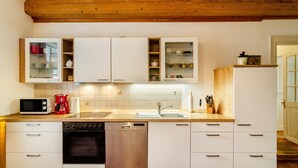 Una cocina con gabinetes blancos, lavavajillas, microondas y un fregadero.