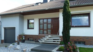 Une maison moderne avec une porte d’entrée, des marches, un petit jardin et un garage.