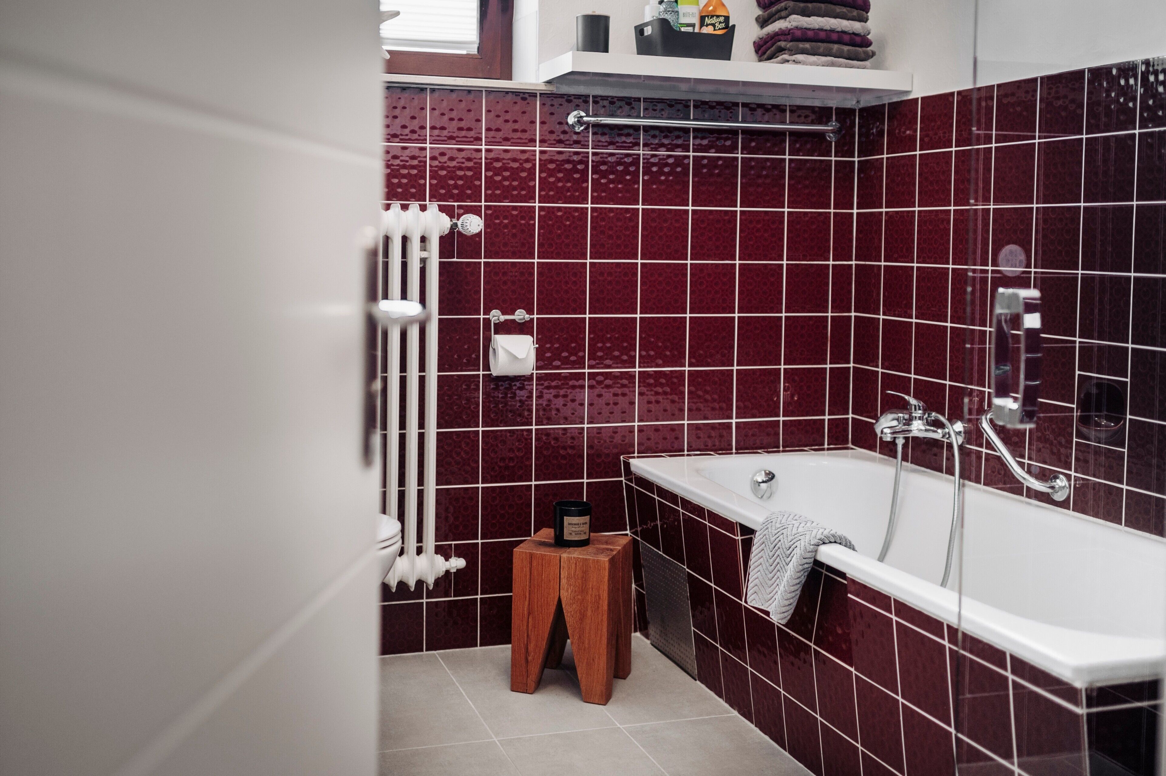 A bathroom with a bathtub, a wooden stool, and a radiator.