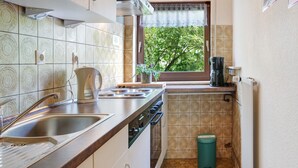 Una cocina con un lavamanos, estufa y ventana con vista a árboles.
