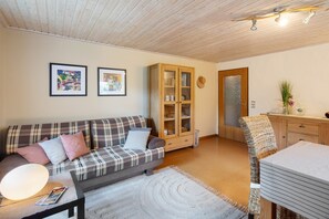 Ein Wohnzimmer mit Sofa, Schrank, Esstisch und Lampe.