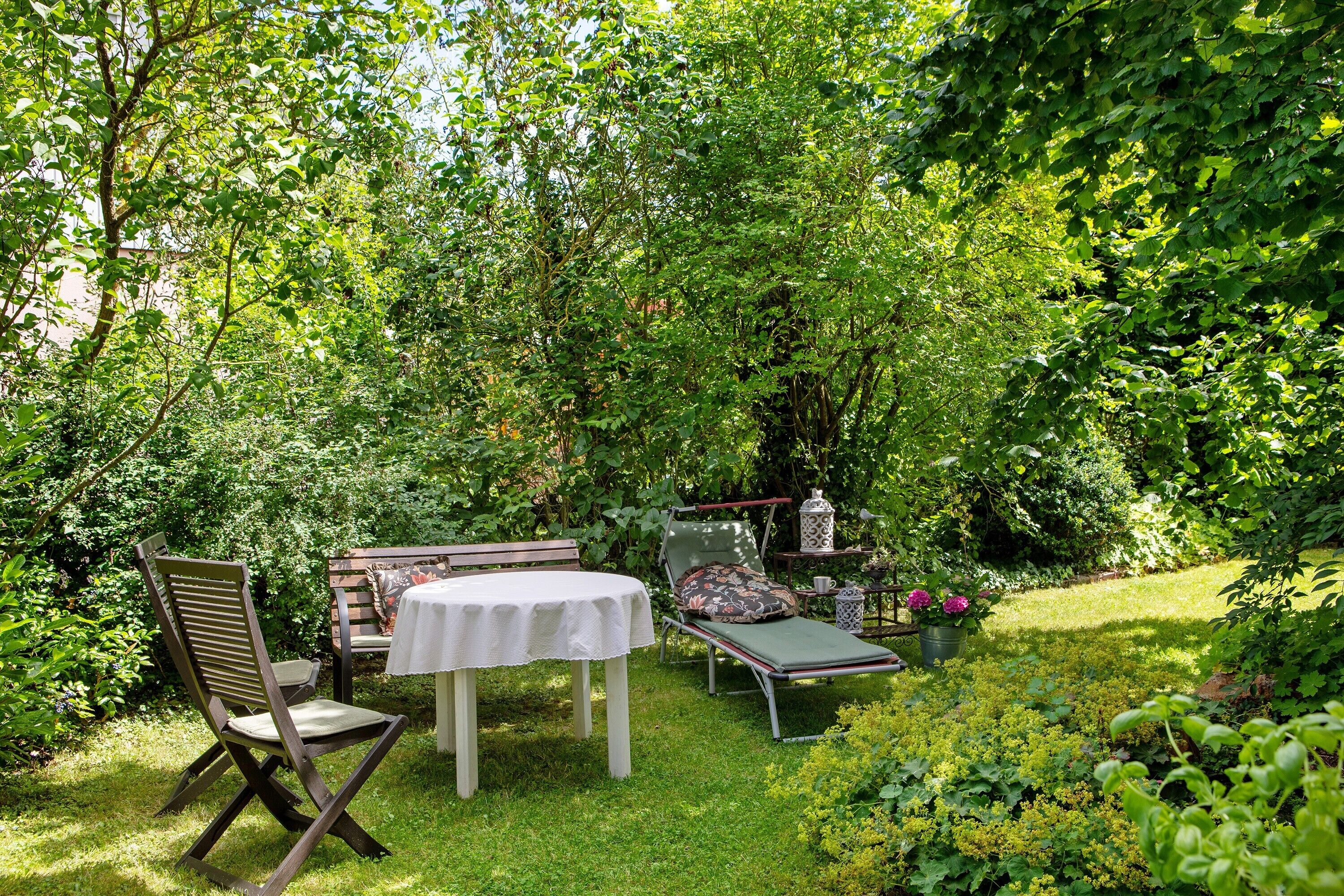A garden with a table, chairs, and a lounge chair.