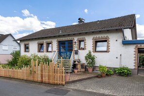 Ein Haus mit blauer Tür, einer kleinen Veranda und Topfpflanzen.