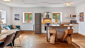 Een moderne keuken met een centraal eiland, houten stoelen en een eettafel.