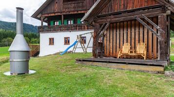 Ein rustikales Holzhaus mit Balkon, Schornstein und Rutsche.