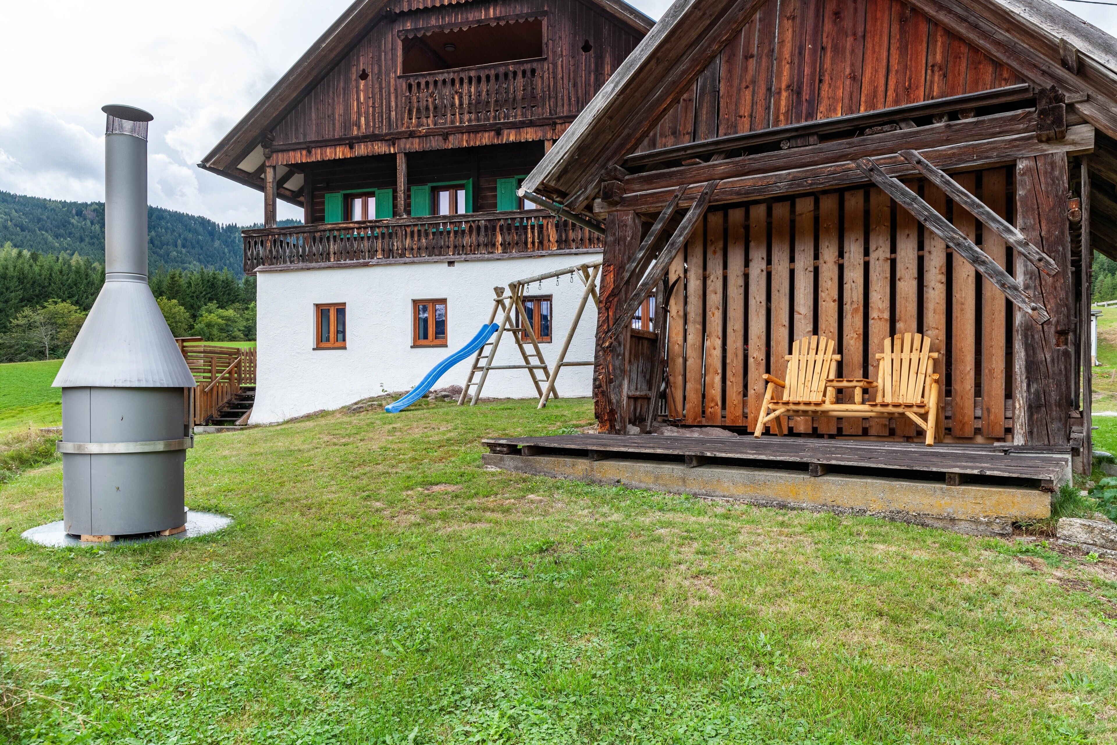 Een rustiek houten huis met balkon, schoorsteen en glijbaan.