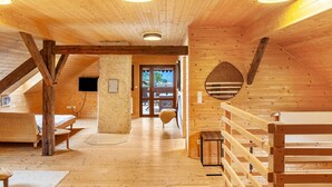 Interior de madera con techo alto, una escalera y vista a través de un ventanal.