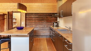 Una cocina moderna con paredes de madera, electrodomésticos de acero inoxidable y una isla de madera con un cuenco azul.