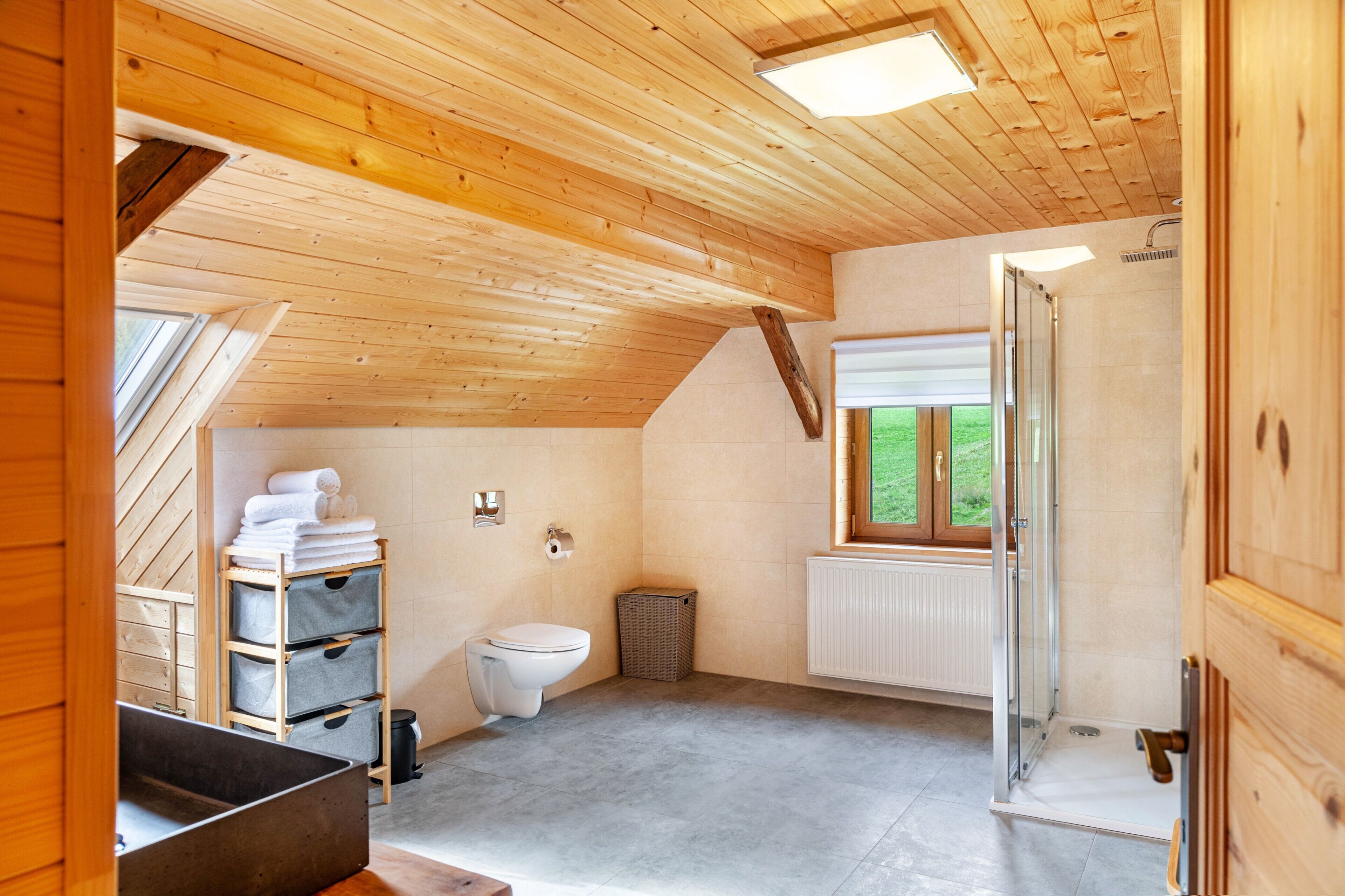 Een houten interieur met een toilet, een raam en een douche.