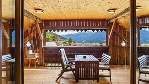 Un interior de madera con una mesa, sillas, un sillón colgante y vistas a montañas.