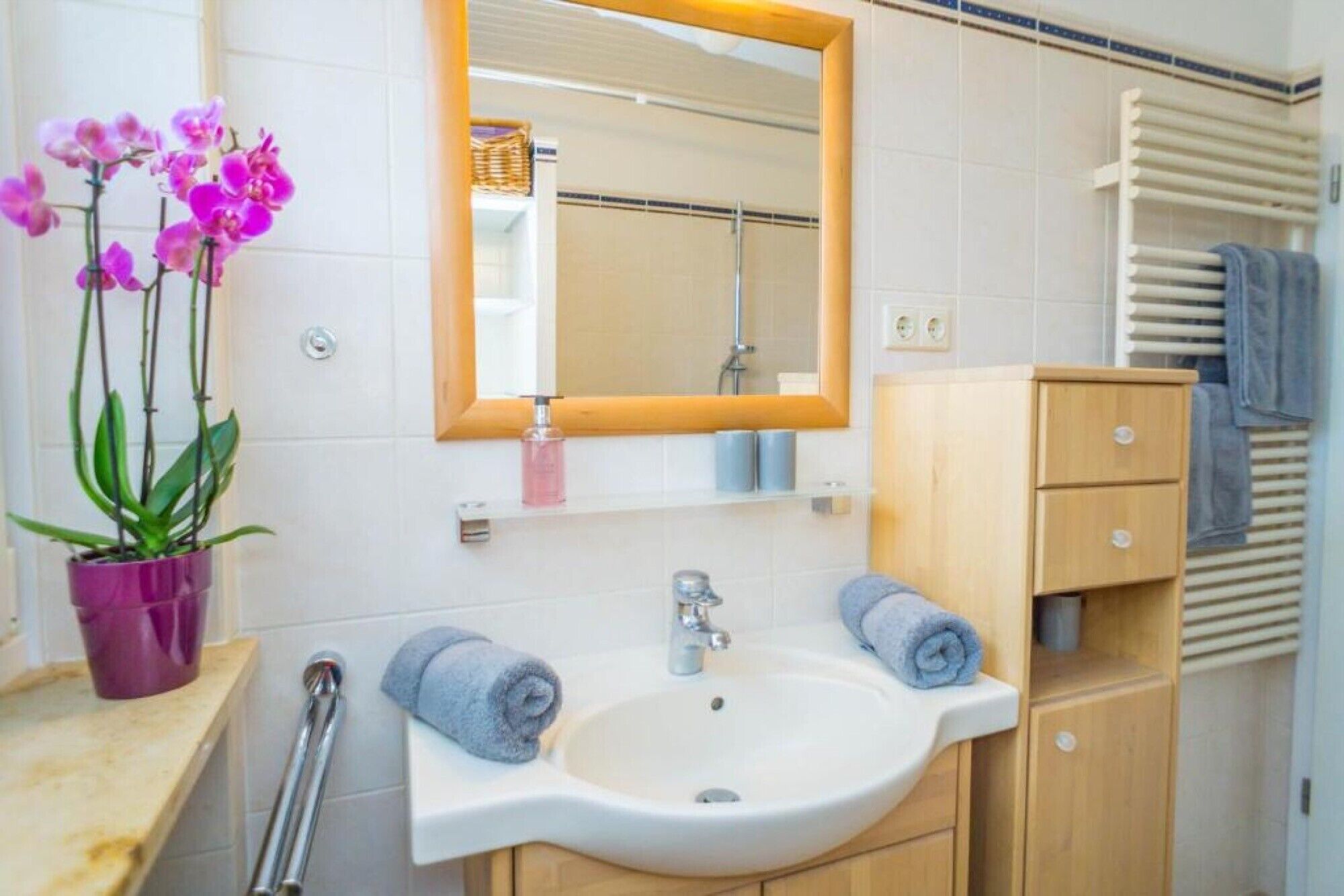 Une salle de bain équipée d’un lavabo, d’un miroir, d’un porte-serviettes et d’un meuble en bois.