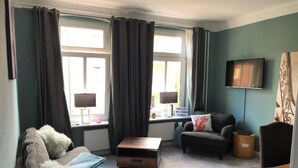 Un salon avec un canapé, une table basse, un téléviseur et un fauteuil.