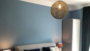 Une chambre à coucher comprenant un lit, des tables de chevet, une lampe, une armoire et un luminaire suspendu.