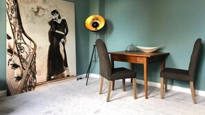 Un coin repas comprenant une table, des chaises, une lampe et un grand tableau accroché au mur.
