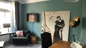 Un salon avec un canapé, une table basse, un téléviseur, un tableau et une lampe.