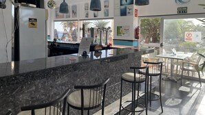 A bar area with a marble counter, hanging blue pendant lights, and bar stools. - Ocean View 2 (Los Cristianos)