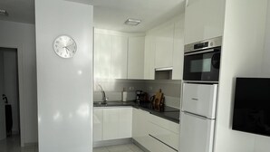 A modern kitchen with white cabinets, a stainless steel oven, and a built-in microwave. - Ocean View 2 (Los Cristianos)