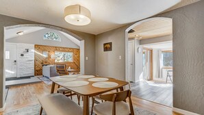 A spacious dining area with a wooden table and chairs, a stone wall, and a large window.
