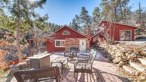 A red cabin with a fireplace, outdoor seating, and a stone wall.
