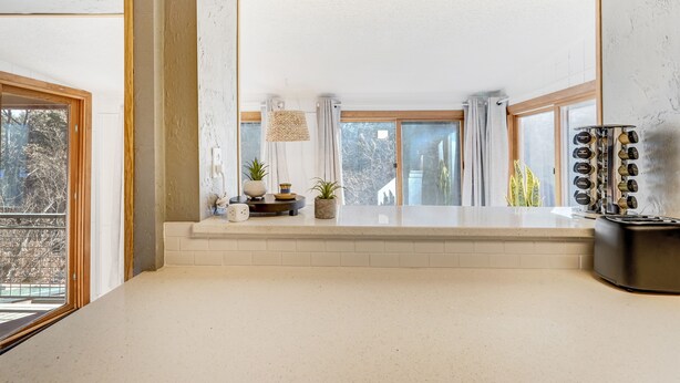 A modern kitchen with a large window, a built-in oven, and a coffee machine.