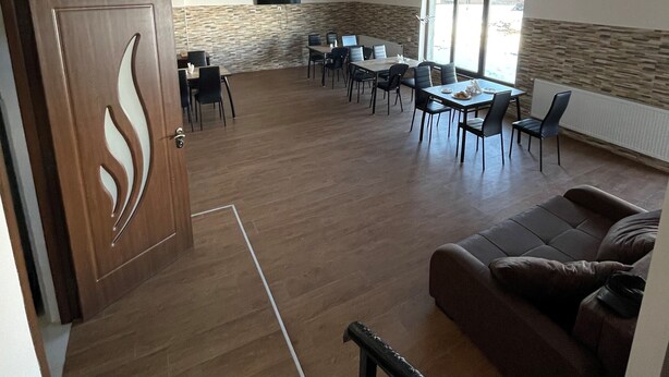 Amplia sala de estar con una mesa de comedor y sillas, un sofá y una escalera que sube a otro nivel.