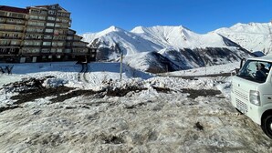 Paisaje montañoso cubierto de nieve con un edificio de varios pisos en primer plano.