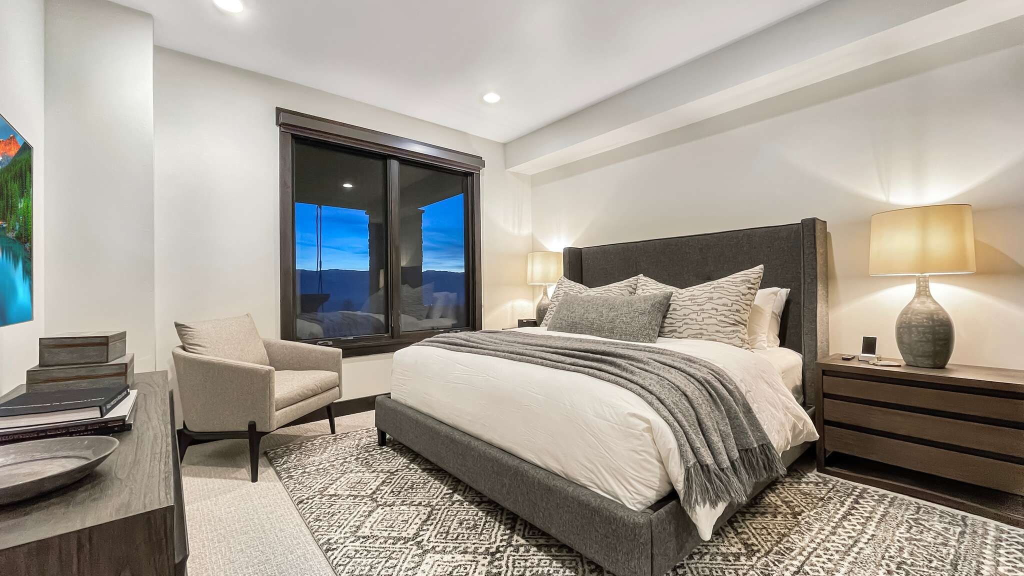 A modern bedroom with a large bed, a desk, and a chair.