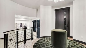 Un intérieur moderne avec un escalier, une grande œuvre d’art et une porte aux teintes sombres.