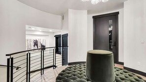 A modern interior with a staircase, a large artwork, and a dark-toned door.