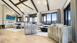 A spacious living area with a stone wall, large windows, and a modern chandelier.