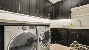 A laundry area with two front-loading washing machines, a sink, and dark cabinets.