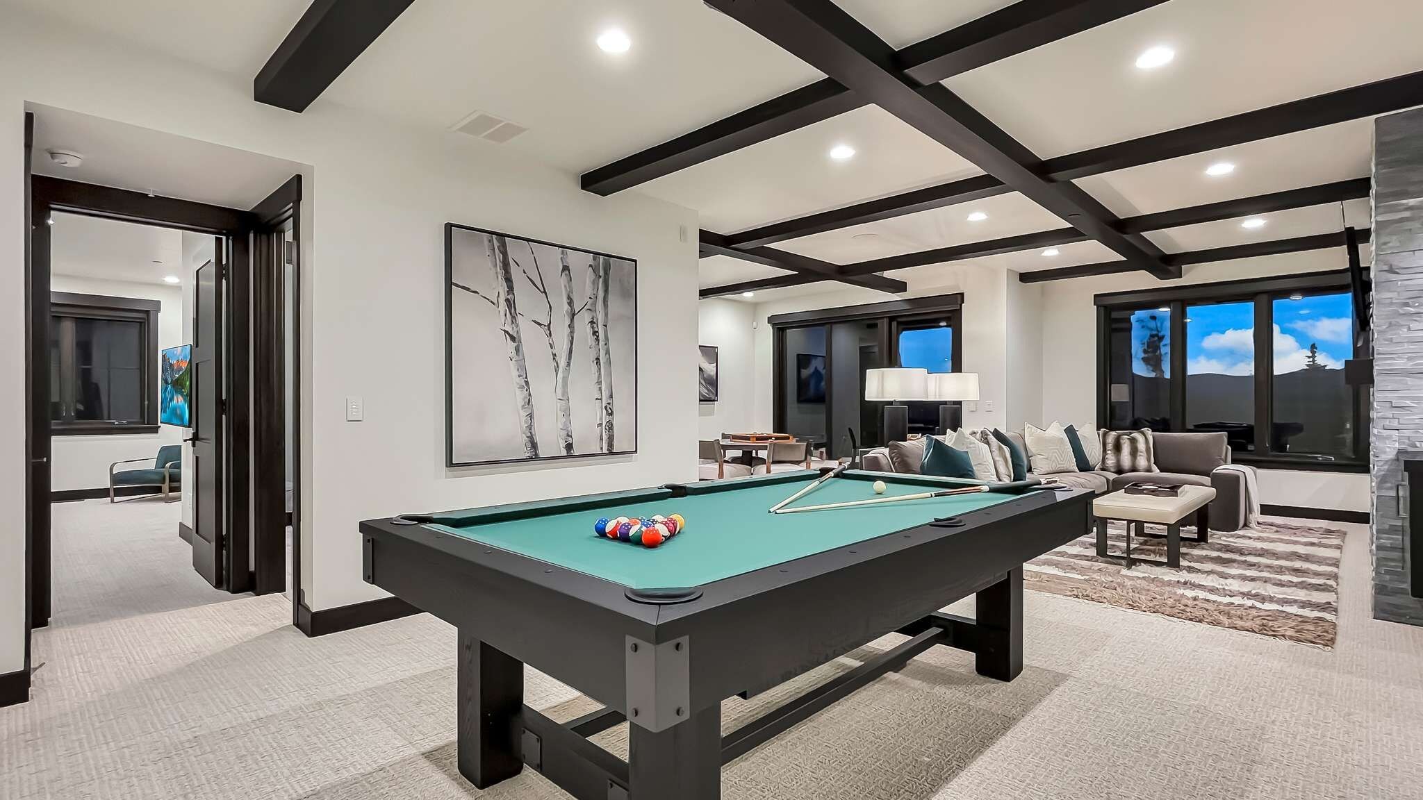 Een pooltafel in een moderne woonkamer met een open haard, een bank en een televisie.