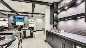 Une cuisine moderne avec des meubles de couleur sombre, un grand îlot central et un mur d’accent en pierre.