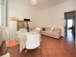 Un salon comprenant une table à manger, deux chaises, un canapé et un meuble.