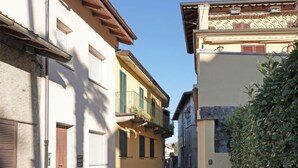 Uma rua estreita com edifícios em ambos os lados, com varandas e persianas.
