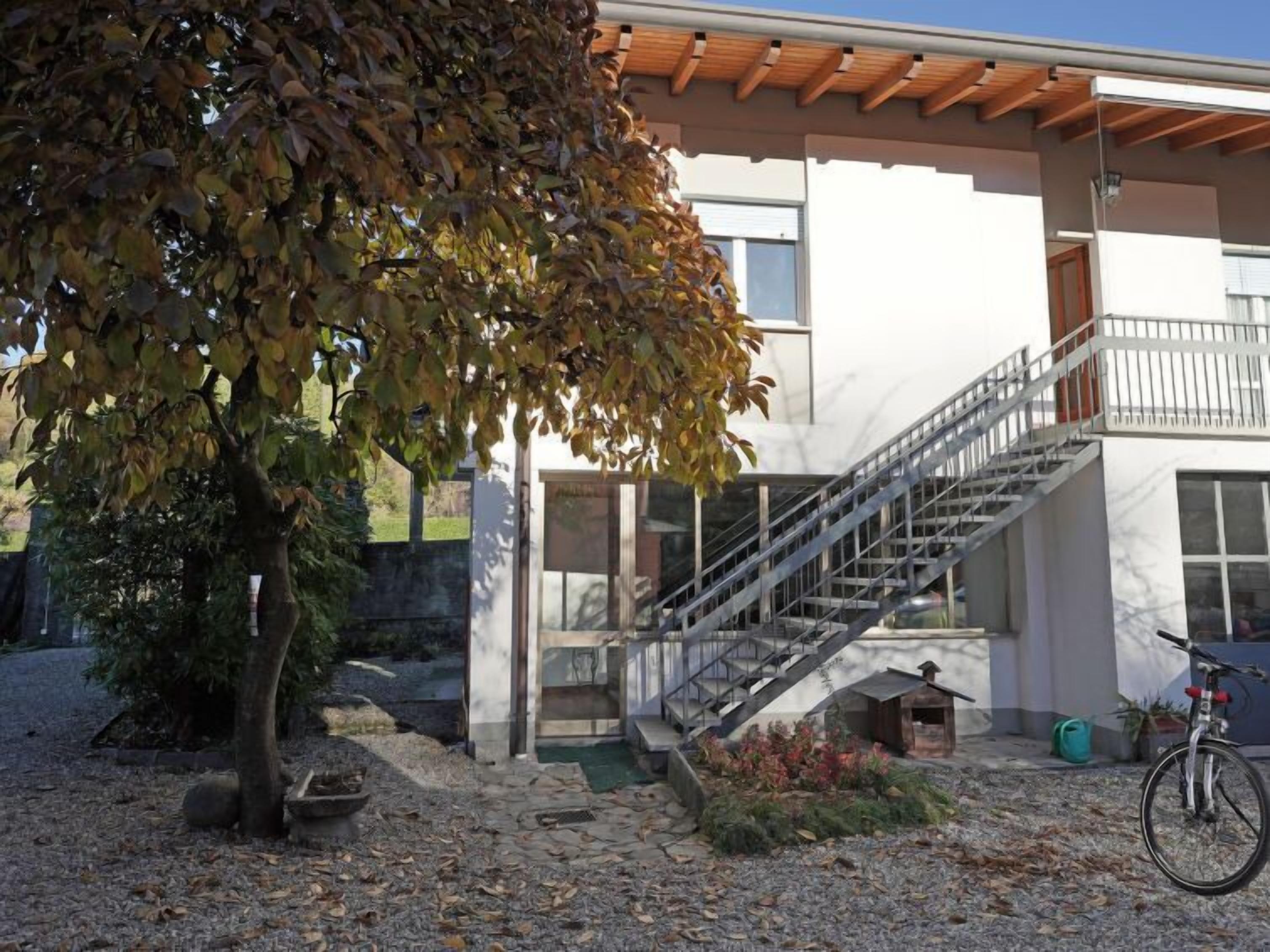 Ein modernes Haus mit einer Holzterrasse, einer Treppe und einem Fahrrad.