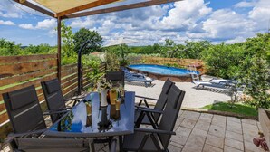 An outdoor patio with a pool, wooden deck, and a covered seating area. - Vacation home Mimosa by Interhome (Pula/Rakalj)