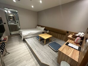 A hotel room with a bed, a wooden table, a small desk, a basket of towels, and a kettle. - MICHI HOTEL LUOONG (Luodong)