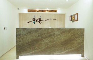 A reception desk with a wooden backdrop and a sign that reads "Michi Hotel". - MICHI HOTEL LUOONG (Luodong)