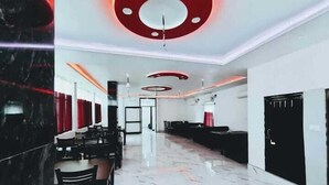 Un hall d’hôtel moderne avec un sol en marbre, des meubles noirs et blancs et des luminaires circulaires rouges au plafond.