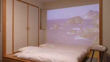 Un dormitorio con una cama, un armario de madera y una pantalla de proyección que muestra una escena costera.