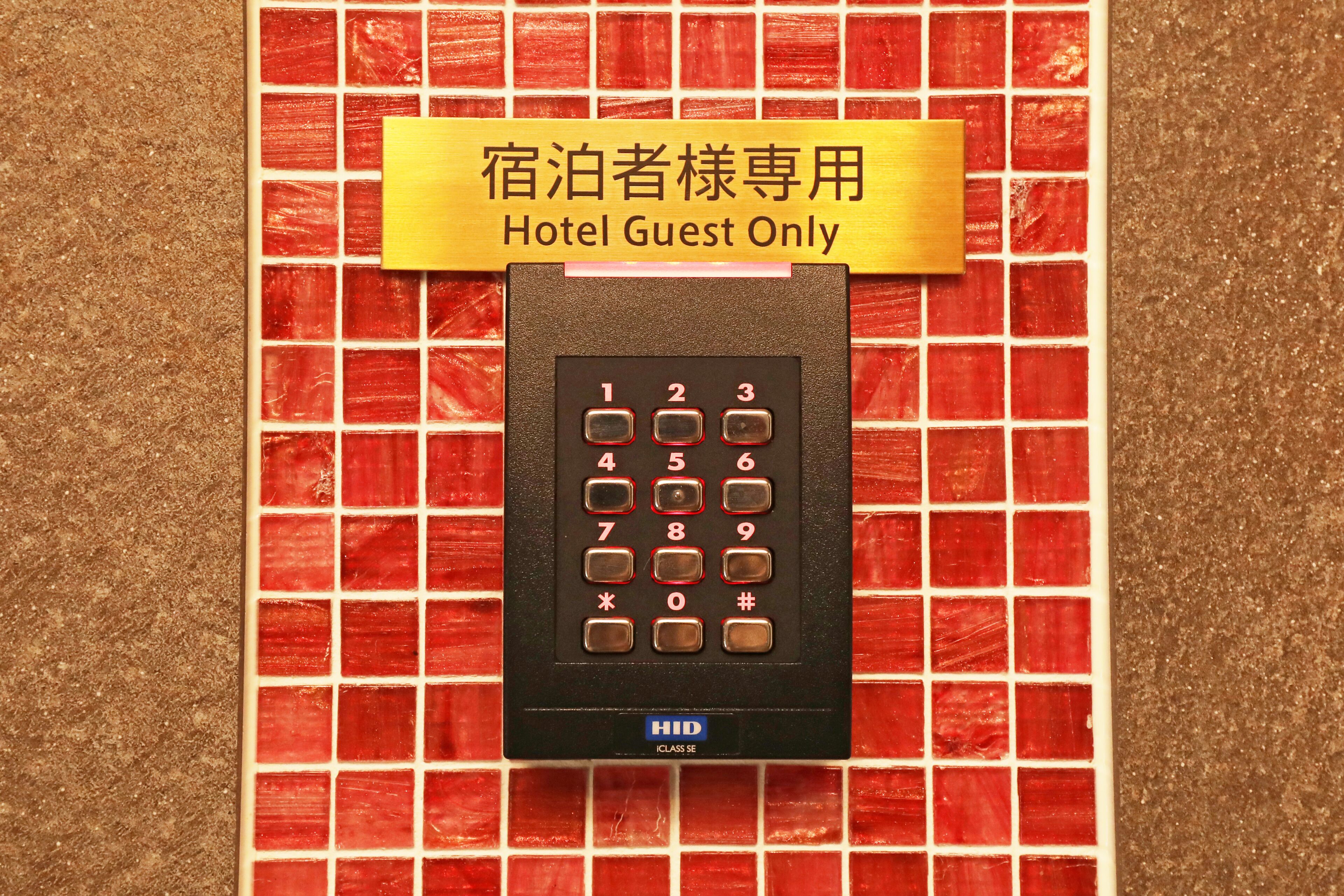 Ein elektronisches Keypad in einem Hotelzimmer, mit einem Schild mit der Aufschrift 'Nur für Hotelgäste' darüber.
