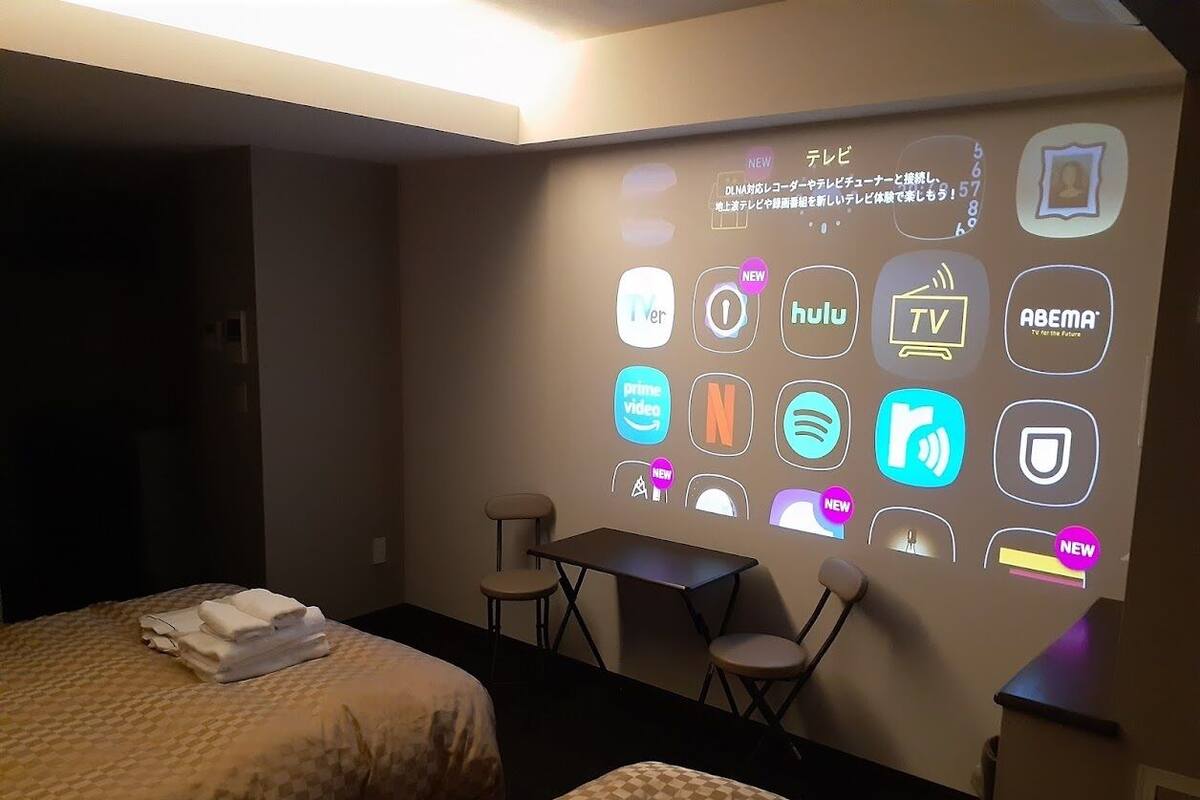 Une chambre d’hôtel avec deux lits, un bureau et un mur où sont affichés différents pictogrammes représentant les services proposés.